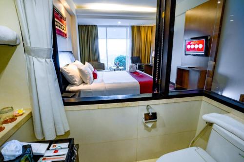 a hotel room with a bed and a mirror at Emersia Hotel and Resort in Bandar Lampung