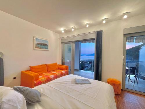 a bedroom with a bed and a couch and a balcony at Seaview Couple Studio with pool-Przno in Pržno