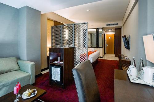 a living room with a couch and a room with a bed at Emersia Hotel and Resort in Bandar Lampung