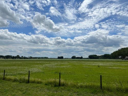 a fence in a field with a cloudy sky at Bij het meertje! in Dirkshorn