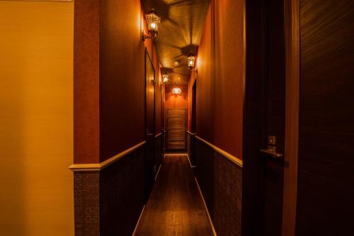 a hallway with a long corridor with wood floors and lights at THE BEEHIVE AIOI in Otaru