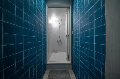 a blue tiled bathroom with a shower and a toilet at THE BEEHIVE AIOI in Otaru