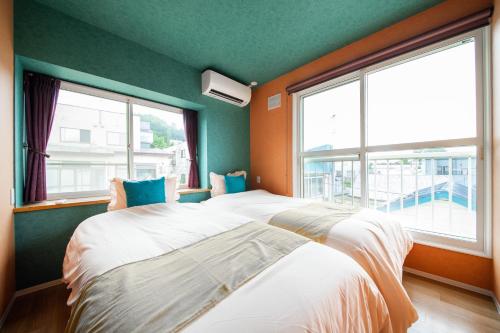 two beds in a room with green walls and windows at THE BEEHIVE AIOI in Otaru