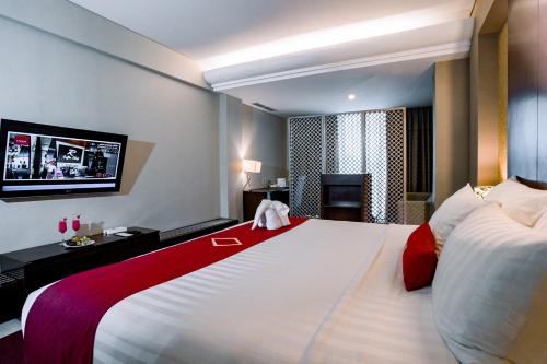 a hotel room with a large bed and a television at Emersia Hotel and Resort in Bandar Lampung