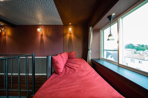 a bedroom with a red bed and a window at THE BEEHIVE AIOI in Otaru