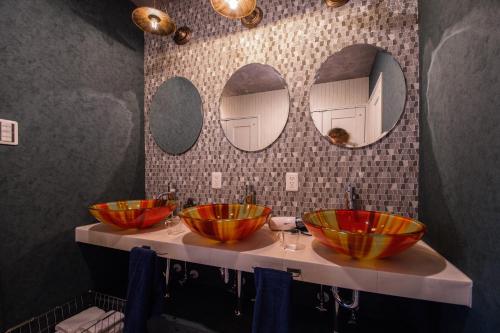 a bathroom with three bowls on a counter with mirrors at THE BEEHIVE AIOI in Otaru