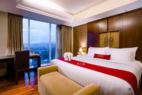 a hotel room with a bed and a desk and a window at Emersia Hotel and Resort in Bandar Lampung