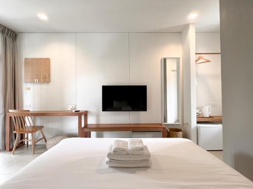 a white bedroom with a bed and a desk at SUNKISS in Bangkok Noi