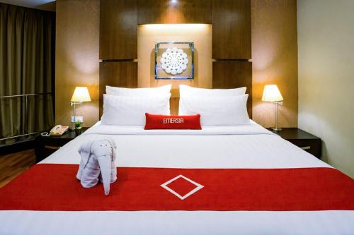 a hotel room with a large bed with a red blanket at Emersia Hotel and Resort in Bandar Lampung