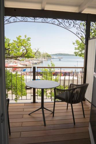 a table and chairs on a balcony with a view of the water at Hafenhotel zu Putbus in Putbus