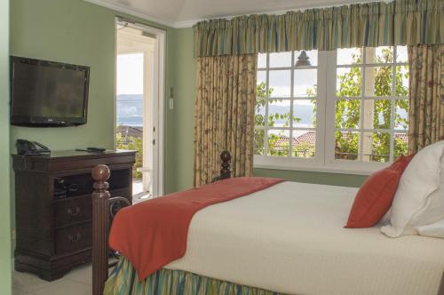 a bedroom with a bed and a flat screen tv at Polkerris Bed & Breakfast in Montego Bay