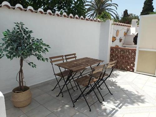 een houten tafel en stoelen op een patio met een potplant bij NUEVA NERJA Pueblo Andaluz Casa Grafton in Nerja