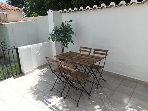 een houten tafel en stoelen met een potplant op een patio bij NUEVA NERJA Pueblo Andaluz Casa Grafton in Nerja