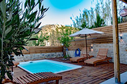 een patio met een zwembad en 2 stoelen en een parasol bij The Cave Villa in Matala