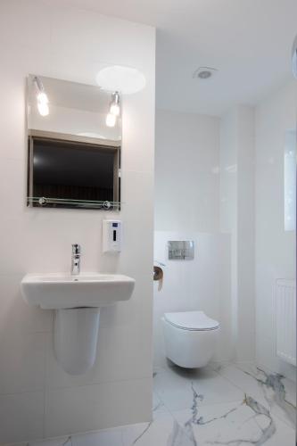 a white bathroom with a sink and a toilet at Western Hills in Gdańsk