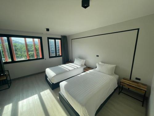 1 dormitorio con 2 camas y 2 ventanas en PRIME TOWN - Posh & Port Hotel PHUKET, en Phuket