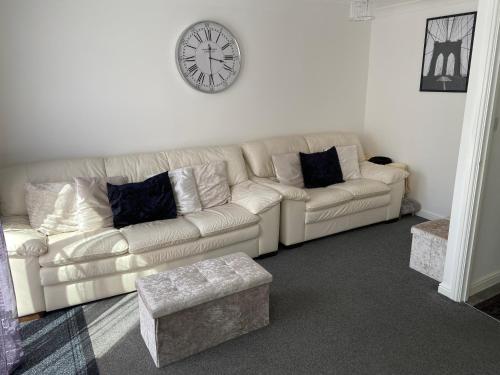 a living room with a couch and a clock on the wall at Stony Apartment House in Doncaster
