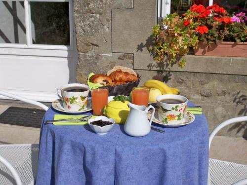 a table with cups of coffee and a basket of fruit at Gite de La Caminais in Pleurtuit