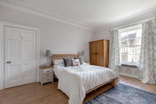 a white bedroom with a bed and a window at Glamorous flat near City Centre in Edinburgh