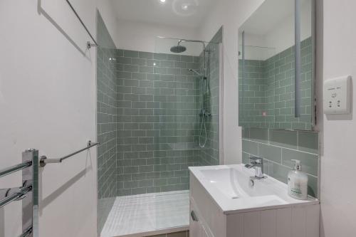a bathroom with a sink and a shower with green tiles at Glamorous flat near City Centre in Edinburgh