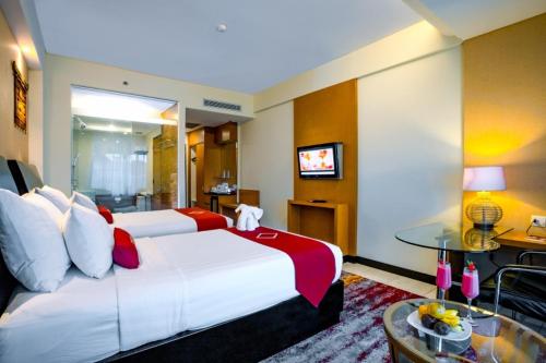 a hotel room with a large bed and a table at Emersia Hotel and Resort in Bandar Lampung