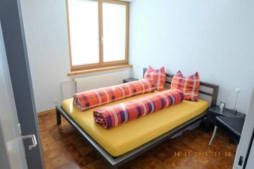 Haus Luegisland, 1-4 Gäste في أروسا: سرير اصفر مع مخدات عليه في غرفه