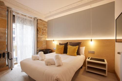 1 dormitorio con 1 cama blanca grande con almohadas amarillas en Pensión Aia, en San Sebastián