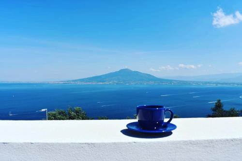 a blue coffee cup sitting on a ledge overlooking the ocean at BLUE 51 in Vico Equense