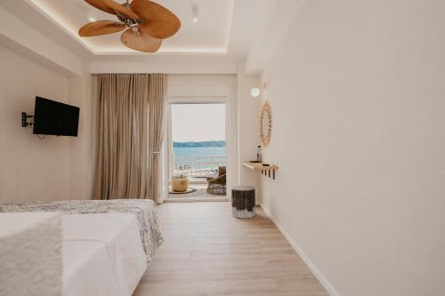 Trinity Suites Ammouliani Hospitality في أمولياني: غرفة نوم مع مروحة سقف وإطلالة على المحيط