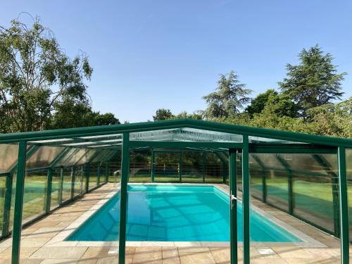 a glass pavilion over a swimming pool with a roof at Large House On Farm With Own Heated Pool, As Seen On BBC TV in Cullompton