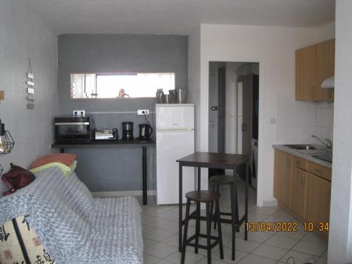 une cuisine avec un réfrigérateur blanc et une table dans l'établissement naturiste, au Cap d'Agde