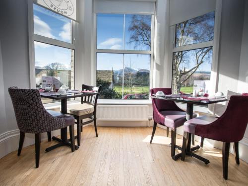 un comedor con mesas, sillas y ventanas en LakeSide House, en Keswick