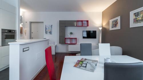 Tagiura 8 في ميلانو: مطبخ وغرفة معيشة مع طاولة وكراسي بيضاء