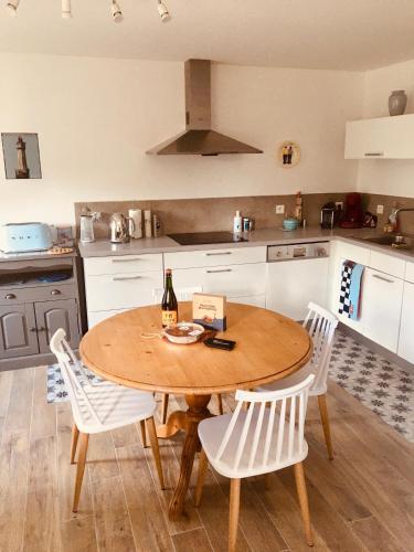 - une cuisine avec une table en bois et des chaises blanches dans l'établissement TY JACQ, à Tréguennec