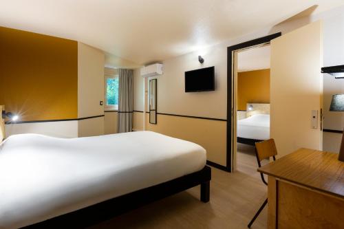 a bedroom with a large white bed and a mirror at Greet Hôtel Villeneuve la Garenne - rénové in Villeneuve-la-Garenne