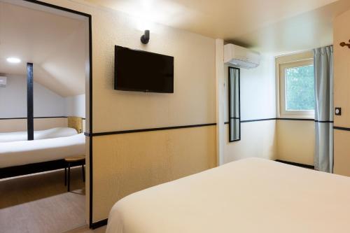 a hotel room with a bed and a television at Greet Hôtel Villeneuve la Garenne - rénové in Villeneuve-la-Garenne