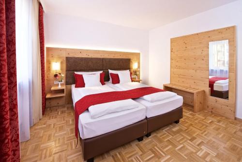 ein Schlafzimmer mit einem großen Bett mit roten und weißen Kissen in der Unterkunft Park Hotel Laim Serviced Apartments in München