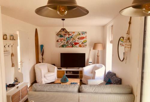 een woonkamer met een bank, 2 stoelen en een televisie bij TY JACQ in Tréguennec