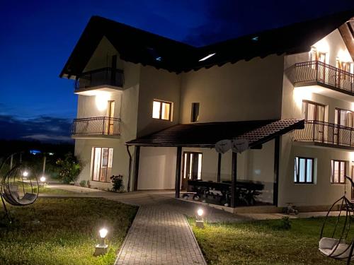a large white building with a patio at night at Pensiunea Ivoire in Avrig