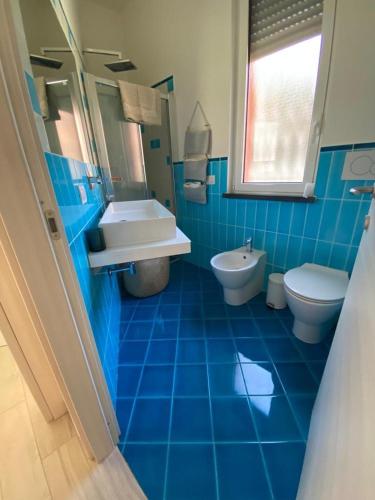 a blue tiled bathroom with a sink and a toilet at La Casa di Greta in Celle Ligure