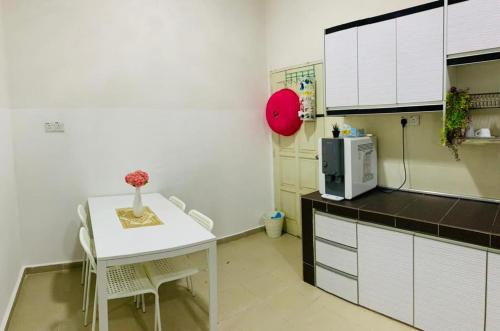a small kitchen with a table and a microwave at Nurul Amin Guest House Pantai Cahaya Bulan Kota Bharu in Kota Bharu