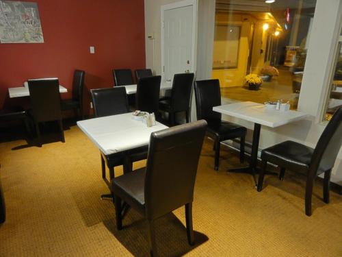 a dining room with white tables and black chairs at Port Augusta Inn in Comox