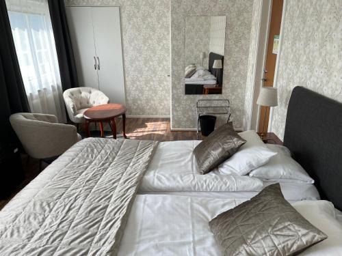 a bedroom with a large white bed and a chair at Hotell Bele in Trollhättan