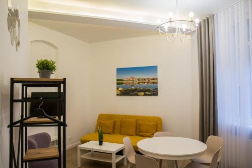 a living room with a yellow couch and a table at P&M Apartament by Rentoom in Toruń