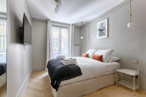 une chambre blanche avec un lit et une télévision dans l'établissement Unique Luxury Parisian flat 2BR/6P -Champs Elysées, à Paris