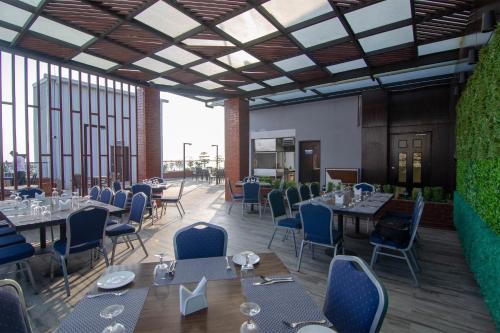 a rendering of a restaurant with tables and chairs at Pearl Harbour Business Hotel in Chittagong