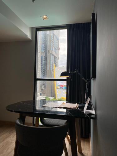 a black desk with a lamp and a window at The Quarter Ladprao by UHG in Bangkok