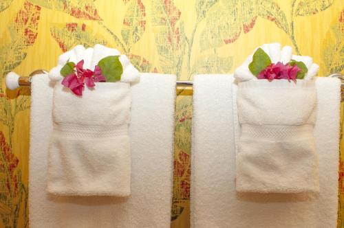 a towel rack with white towels with flowers in them at Polkerris Bed & Breakfast in Montego Bay