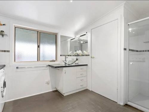 a white bathroom with a sink and a shower at Chill at our Igloo cottage - 100m stroll to beach in Portarlington