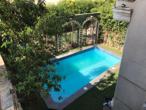 a swimming pool in a yard with a fence at Trio Villa with coverable private pool in compound near Mall of Egypt in Sheikh Zayed
